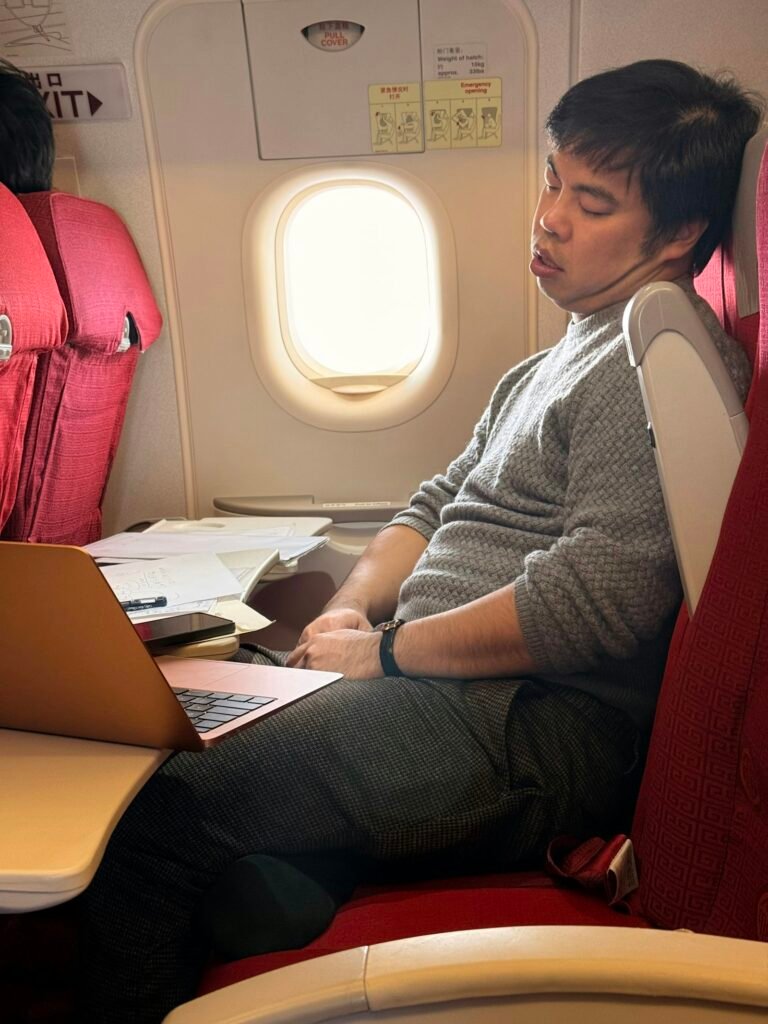 Man sleeping on airplane with laptop on tray