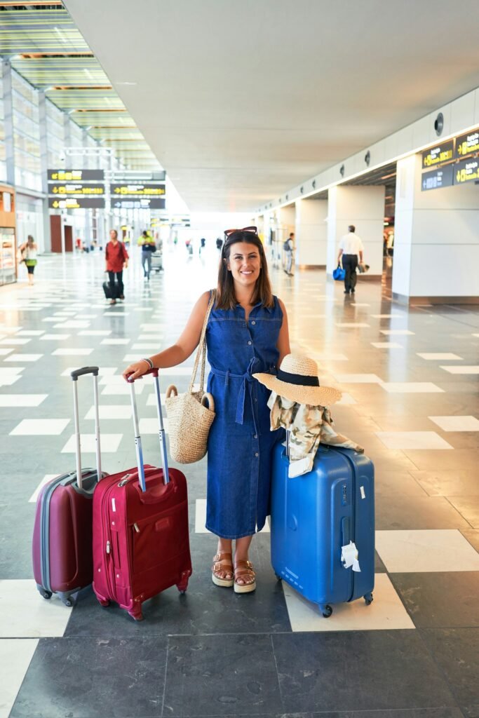 What to wear on a long-haul flight – traveller in a denim jacket with red luggage